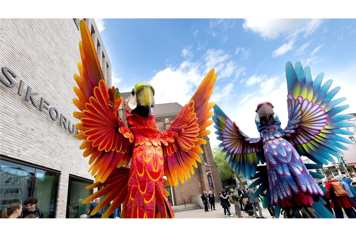 Zwei Papagei-Statuen stehen für die Eröffnungsparade des Figurentheaterfestivals Fidena in Bochum auf der Straße. Mit übergroßen Insekten und seltsamen Lebewesen wurde ein Statement gegen das Artensterben gesetzt.