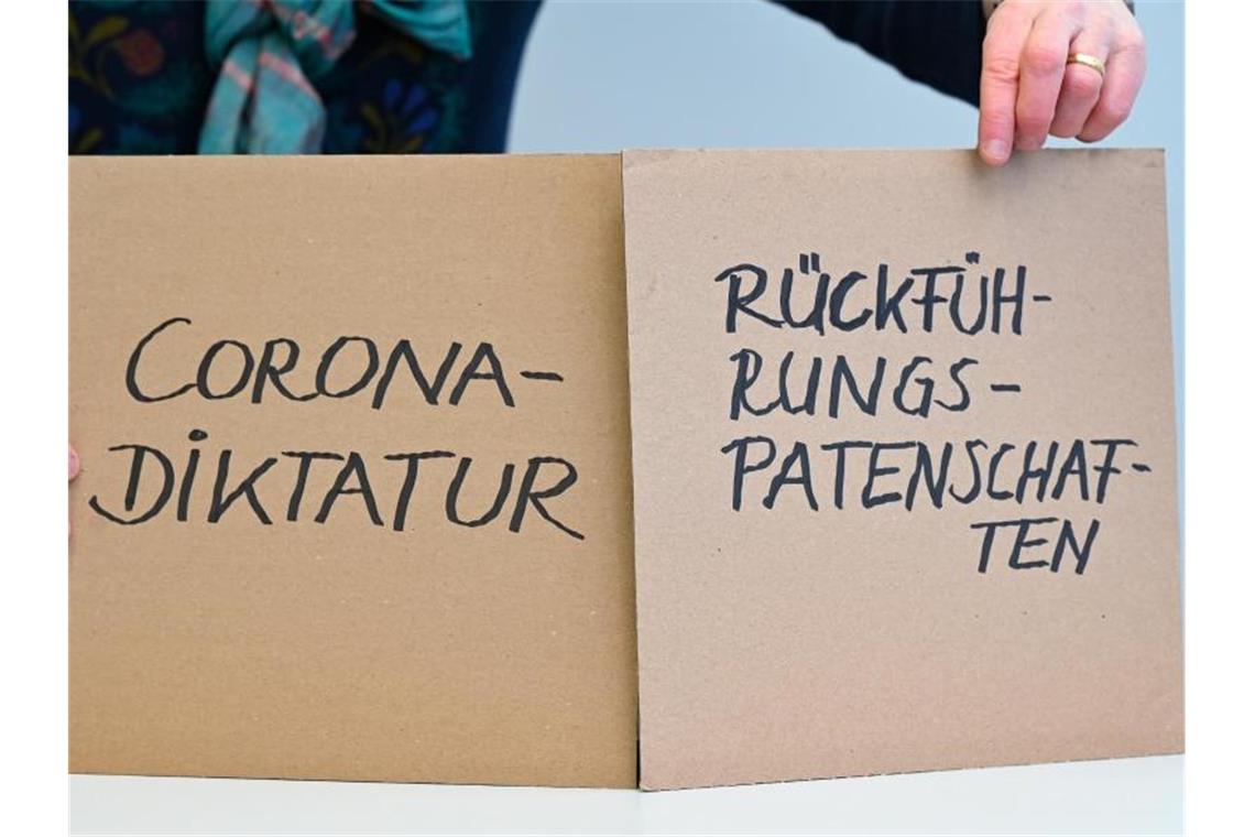 Zwei Pappschilder mit den Aufschriften "Rückführungspatenschaften" und "Corona-Diktatur". Foto: Arne Dedert/dpa