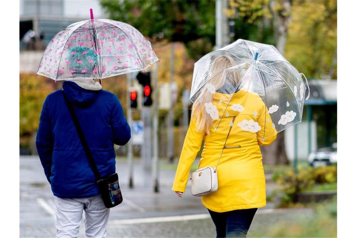 Regen, Wind, Schnee: Ungemütlicher Wochenstart im Südwesten Zwei Passanten gehen mit Regenschirmen durch die Stadt. Foto: Hauke-Christian Dittrich/dpa/Archivbild