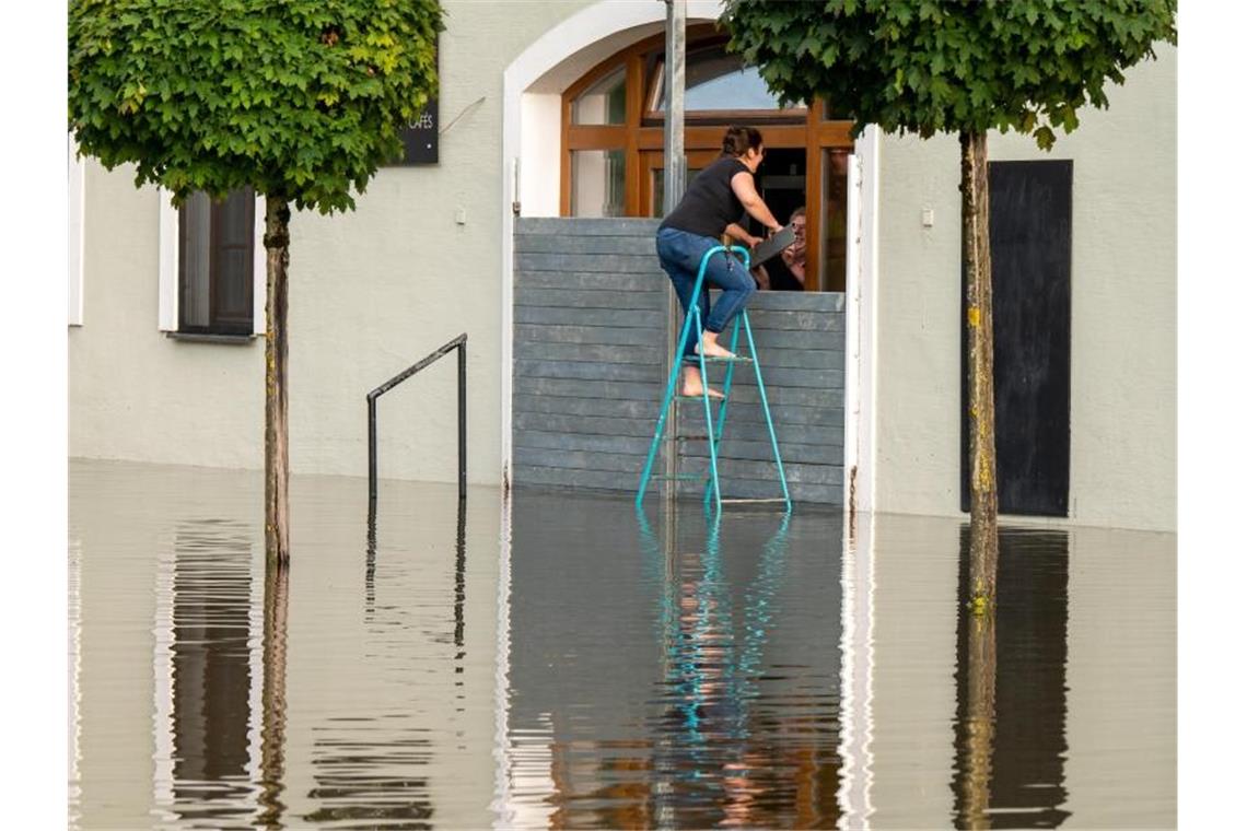 Seehofer: „Wir erleben eine unfassbare Tragödie“ Zwei Personen dichten in Passau den Eingang eines Cafés mit einer speziellen Hochwassersperre ab, um das Gebäude vor dem Wasser der Donau zu schützen. Foto: Peter Kneffel/dpa