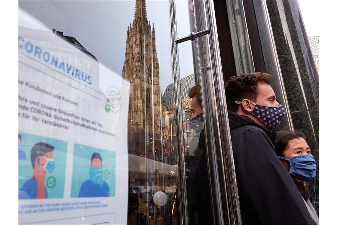 Zwei Personen, die Mund-Nasen-Schutz tragen, stehen in Wien neben einem Hinweisschild für das korrekte Tragen der Mund-Nasen-Bedeckung. Foto: Georges Schneider/XinHua/dpa