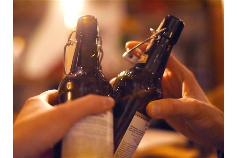 Zwei Personen stoßen in einer Kneipe mit Bier an. Foto: Angelika Warmuth/dpa/Symbolbild