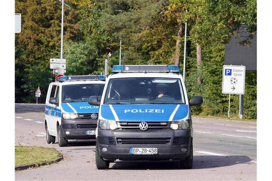 Zwei Polizeiwagen begleiten die Verdächtigen. Foto: Andreas Rosar/Fotoagentur-Stuttgart/dpa