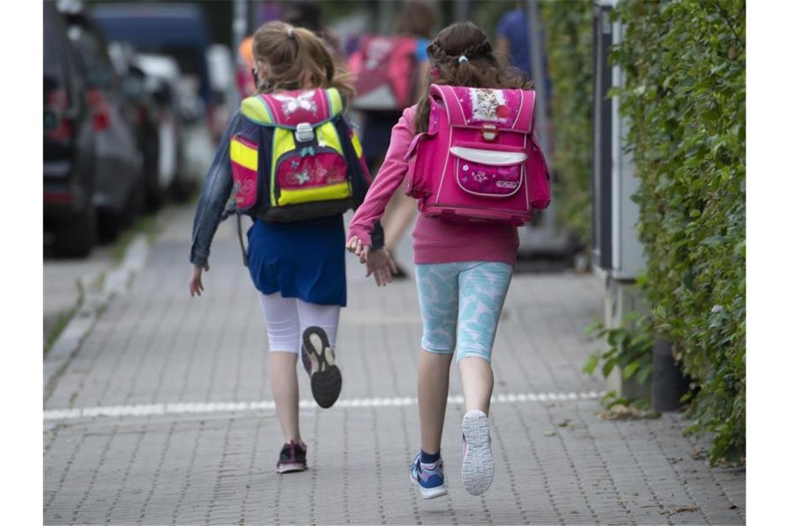 Zwei Schülerinnen einer Grundschule rennen die letzten Meter zum Schulhof. Foto: Boris Roessler/dpa/Symbolbild
