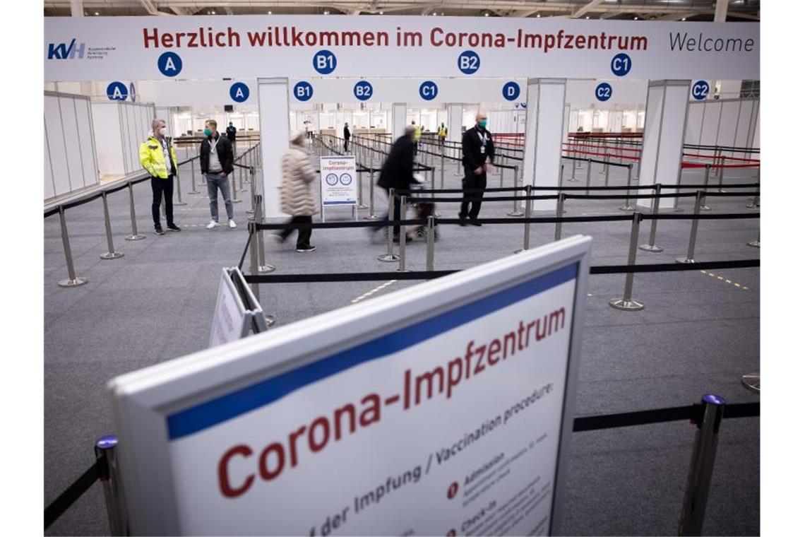 Zwei Senioren (M) sind im Eingangsbereich des Corona-Impfzentrums in den Hamburger Messehallen auf dem Weg zur Impfung. Foto: Christian Charisius/dpa
