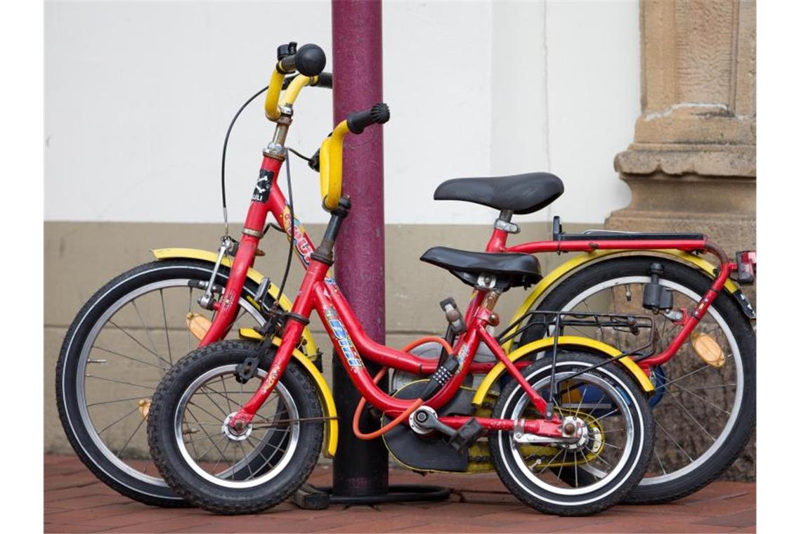 Zwei zusammengeschlossene Kinderfahrräder an einer Straßenlaterne. In Mailand hat ein Sechsjähriger von der Polizei eine neues Rad bekommen. Foto: Friso Gentsch/dpa